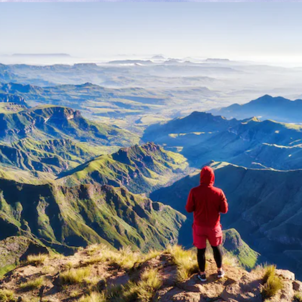 Man standing atop Table Mountain, gazing at the expansive urban landscape of South Africa's wilderness below.