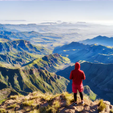Man standing atop Table Mountain, gazing at the expansive urban landscape of South Africa's wilderness below.