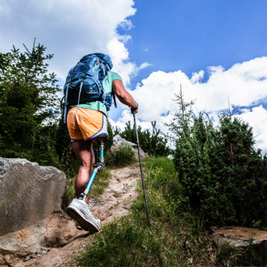 A man with an artificial leg trekking through a scenic landscape, showcasing adaptive adventure travel for differently-abled individuals.
